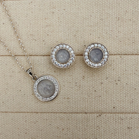 A beautiful set of a matching necklace and earrings in sterling silver surrounded by cubiic zirconia stones with a white silver centre featuring hidden hair inside.