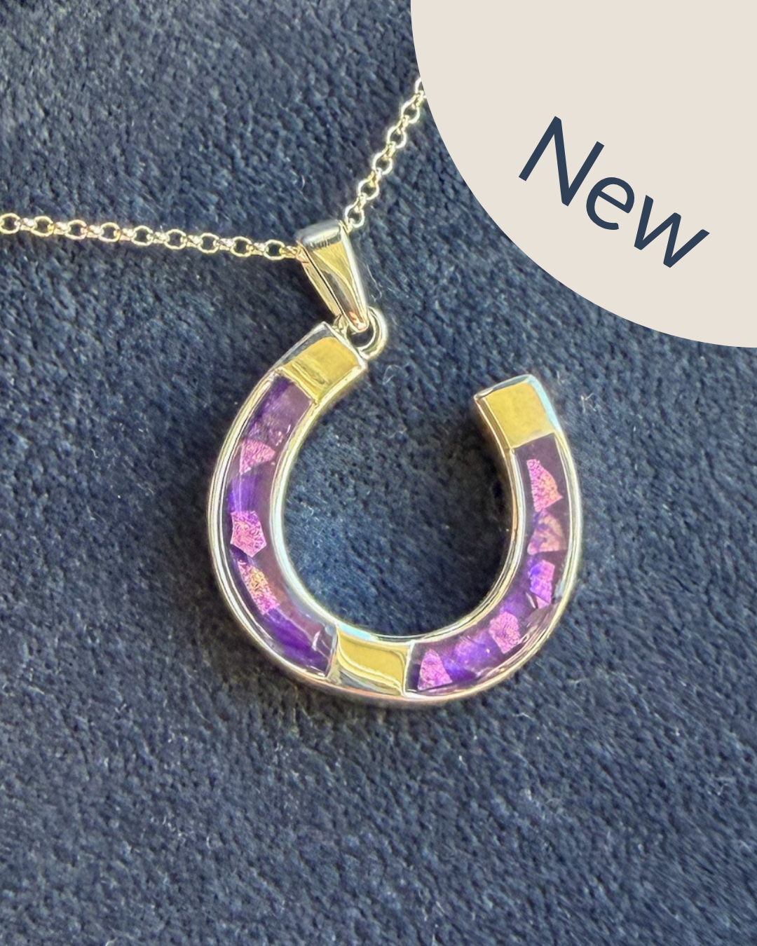 A horseshoe good luck shaped pendant in sterling silver with a sterling silver necklace. The penance has a purple mica with sparkling opal. The pendant can have ashes, hair or fur placed. 