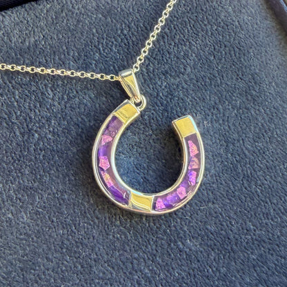 A horseshoe good luck shaped pendant in sterling silver with a sterling silver necklace. The penance has a purple mica with sparkling opal. The pendant can have ashes, hair or fur placed. 