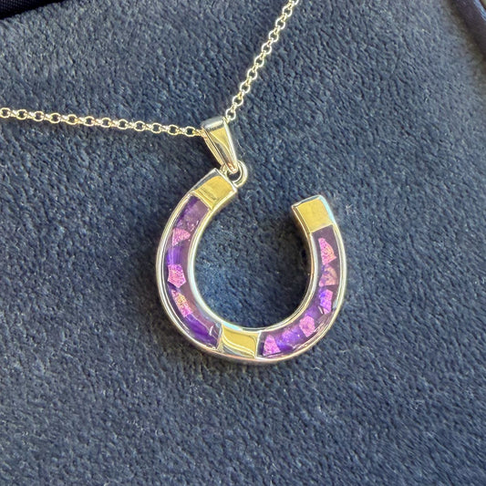 A horseshoe good luck shaped pendant in sterling silver with a sterling silver necklace. The penance has a purple mica with sparkling opal. The pendant can have ashes, hair or fur placed. 