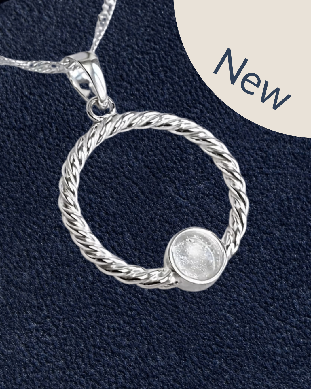 A sterling silver twisted rope pendant necklace with a small round bezel-set clear stone, shown on a textured navy blue background with a beige 'New' badge in the top right corner.