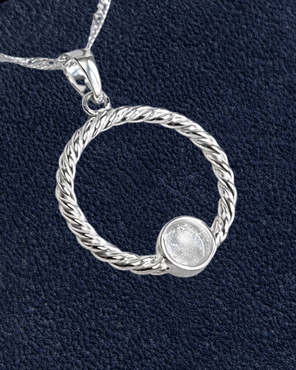 A sterling silver twisted rope pendant necklace with a small round bezel-set clear stone, shown on a textured navy blue background with a beige 'New' badge in the top right corner.