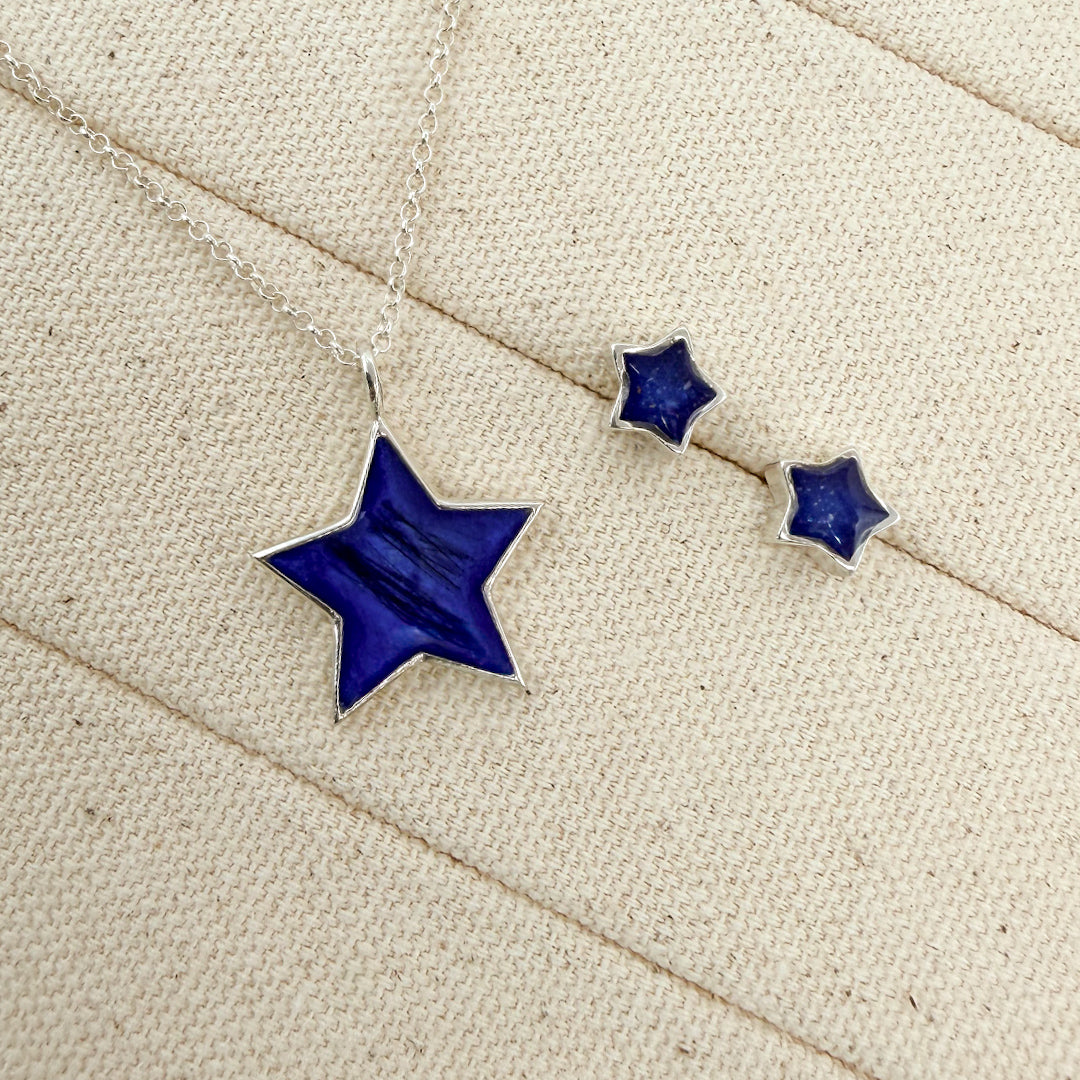 A sterling silver Star necklace and matching Star stud earrings, displayed on a textured beige fabric background.