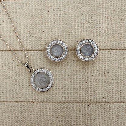 Matching sterling silver necklace and matching stud earrings surrounded with cubic zirconia stones with a white and silver centre featuring a hidden hair inclusion. 