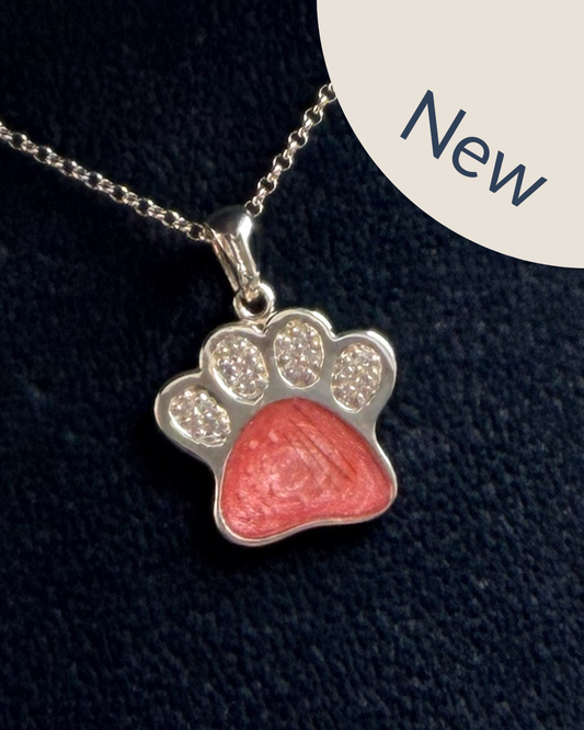 A sterling silver paw print pendant necklace with cubic zirconia with a pink centre with visible hair and ashes.
