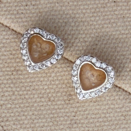 A pair of heart-shaped stud earrings with cubic zirconia borders and champagne centre with visible ash. 