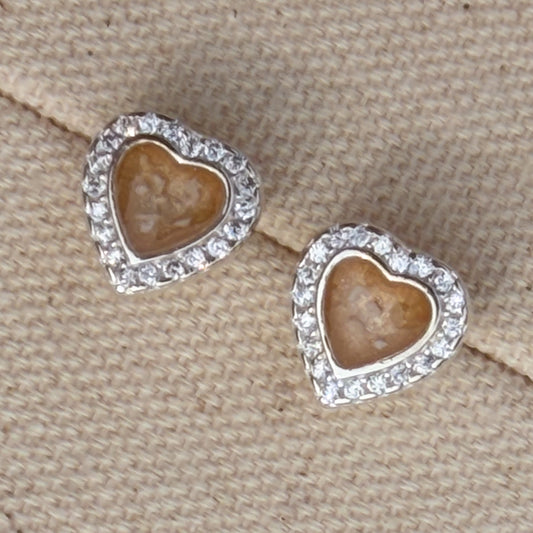 A pair of heart-shaped stud earrings with cubic zirconia borders and champagne centre with visible ash. 