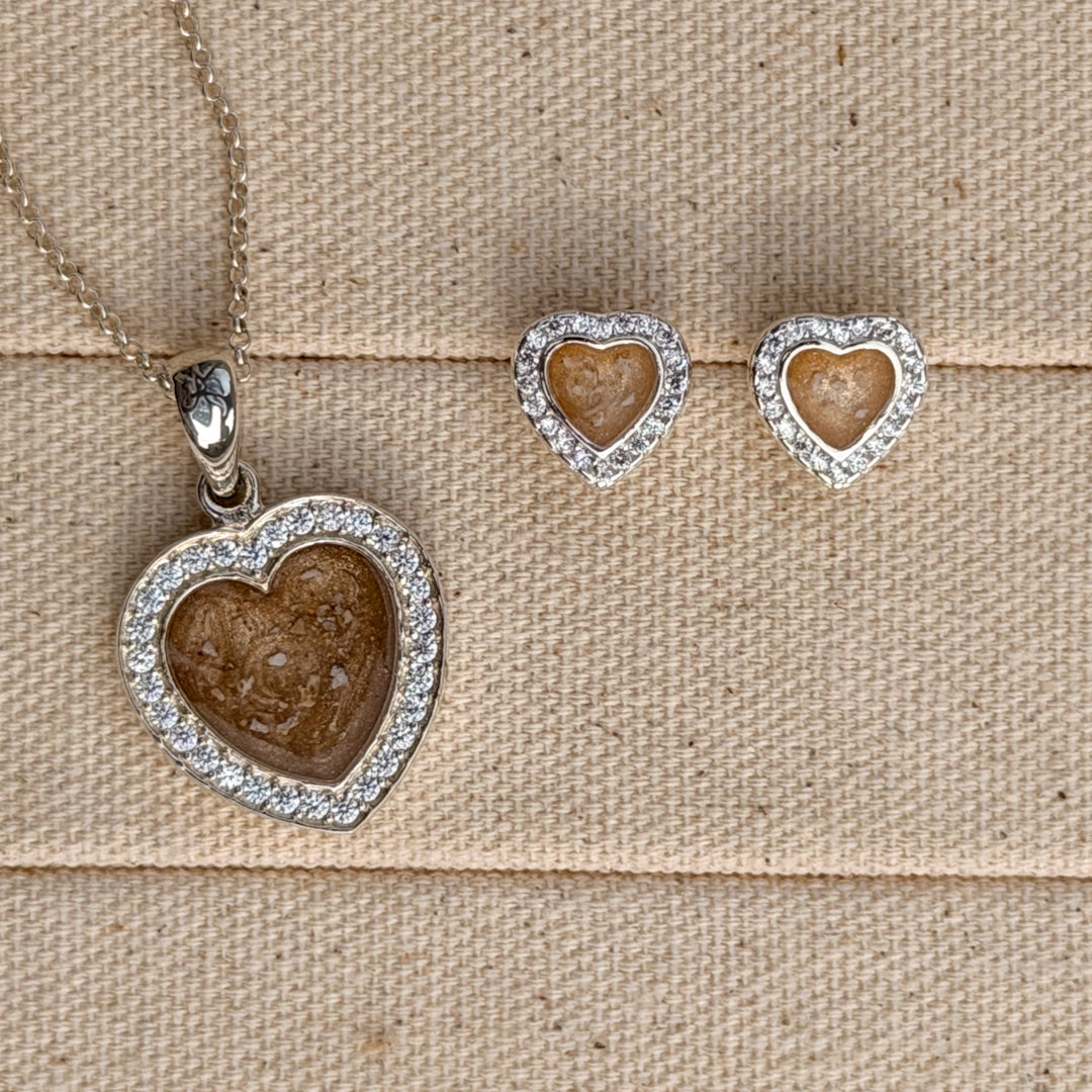 A heart necklace and earring set with cubic zirconia stones and a champagne centre with visible ash. 